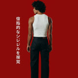 Person wearing a white tank top and black pants on a red background